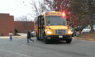 yellow school bus with flashing lights and kids getting off