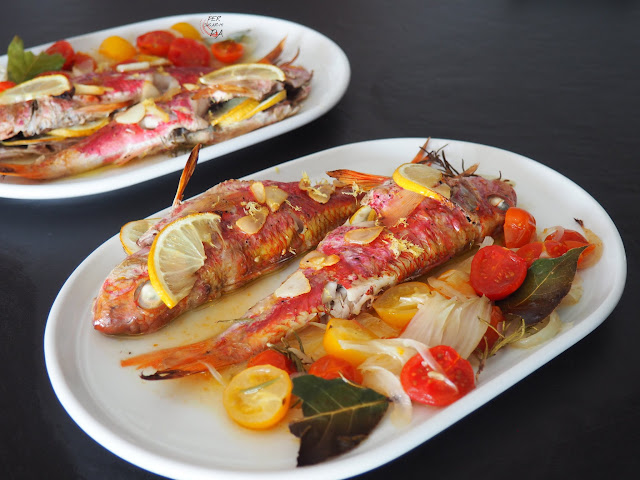 Salmonetes al horno, aromatizados con limón, hierbas aromáticas y ajo, acompañados de una guarnición horneada de cebolleta y tomates cherryes