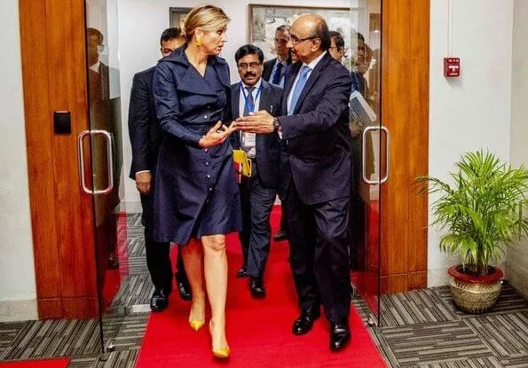 Queen Maxima wore a navy blue trench dress by Jan Taminiau. yellow earrings and Gianvito Rossi yellow metallic pumps