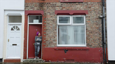 Una solicitante de asilo observa la calle desde la puerta roja de su casa en la ciudad de Middlesbrough, en el noreste del Reino Unido.