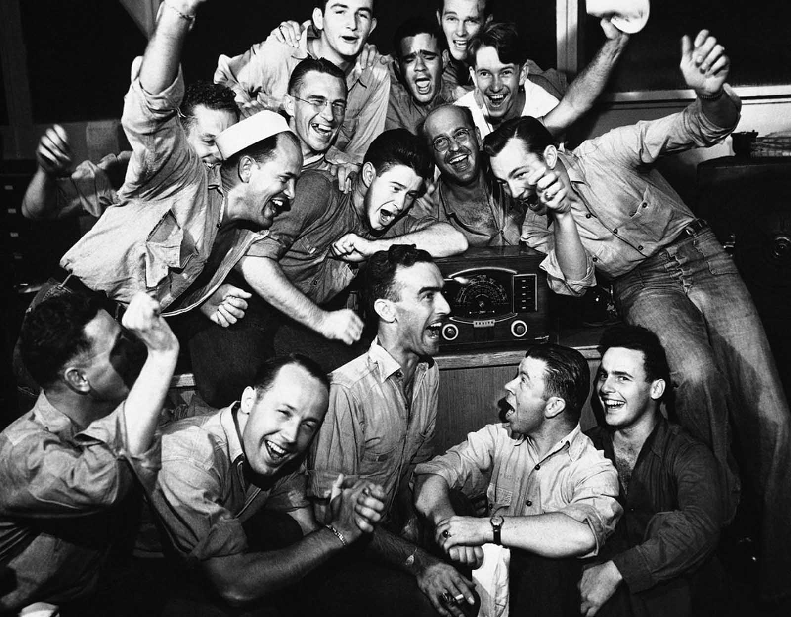 Sailors in Pearl Harbor, Hawaii listen to radio and cheer as Tokyo radio states Japan has accepted the Potsdam surrender terms on August 15, 1945.