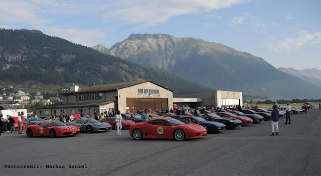 Viele Ferrari in Reihen, vor Haus und Bergen auf Flugplatz Samedan, Engadin, Schweiz