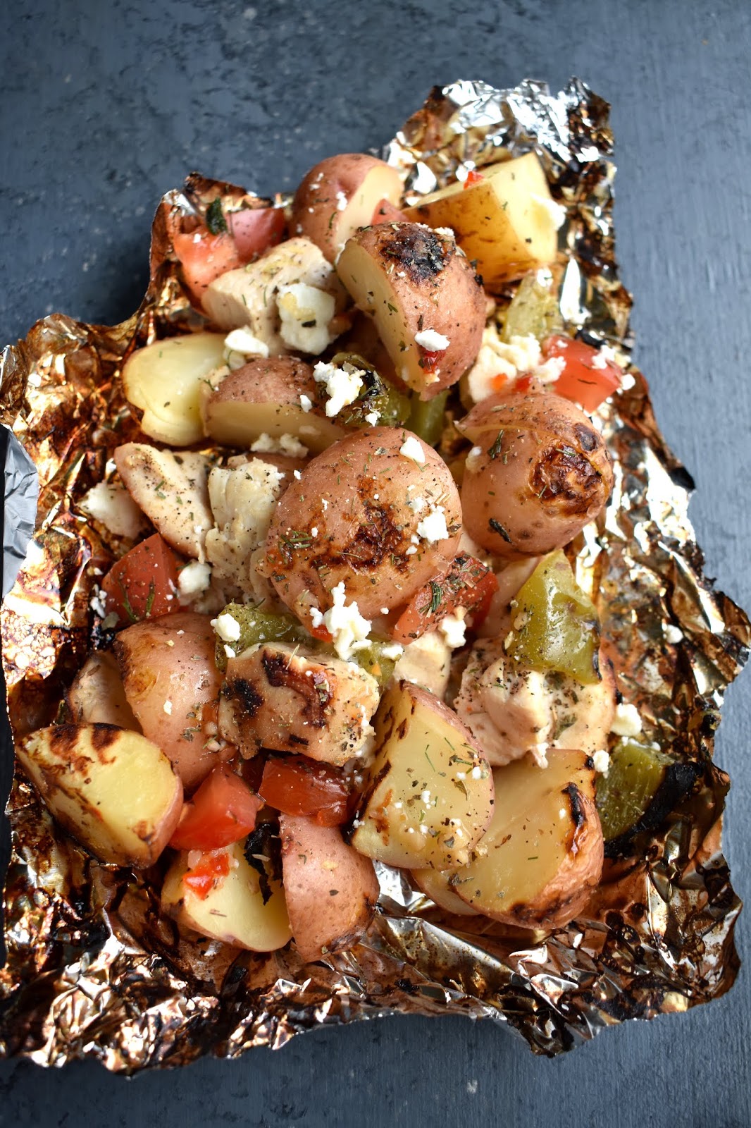 Mediterranean Lemon Chicken and Potatoes are cooked on the grill in a foil packet and are ready in under 30 minutes! Filled with red potatoes, lemon chicken, tomato, dill, green pepper and feta cheese. www.nutritionistreviews.com