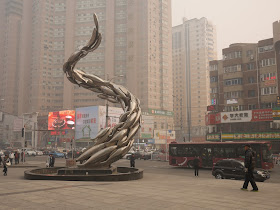 sculpture of fish swimming in a twisted upward direction on a foggy / smoggy day in Dalian, China