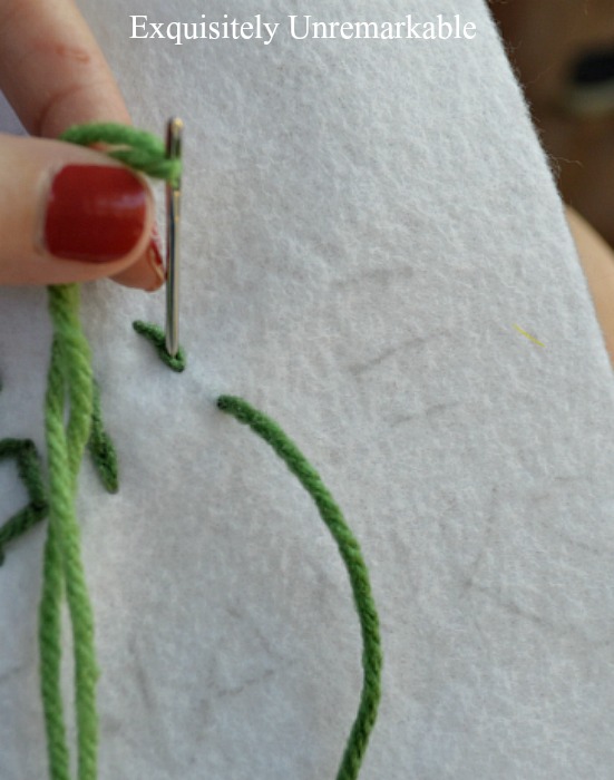Needle with green yard stitching on felt pattern