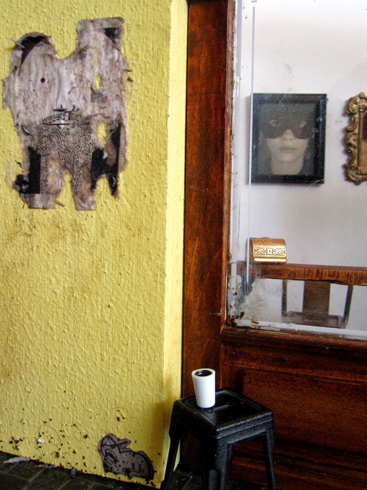 Exterior of a modern dolls' house miniature cafe with paste-ups on the wall.