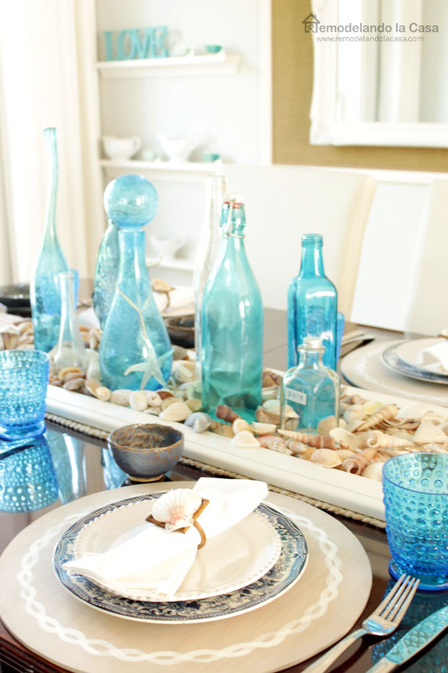 tablescape with blue bottles, shell centerpiece and anchor placemats