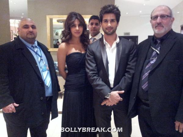 shahid in black suit coat amd priyanka in a black off shoulder dress standing with promoters -  Shahid & Priyanka @London premiere of Teri Meri Kahaani