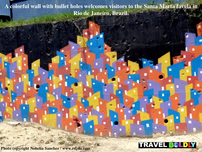 A colorful wall with bullet holes welcomes visitors to the Santa Marta Favela in Rio de Janeiro, Brazil. Photo copyright Nohelia Sanchez / www.rdj4u.com for www.TravelBoldly.com