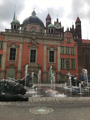 fountains in front of a red building in gdansk