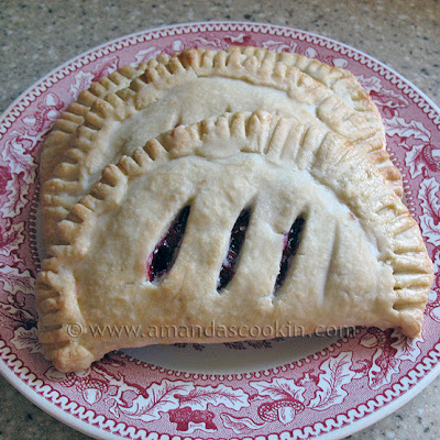 A close up photo of two cherry hand pies resting on a red and white plate.
