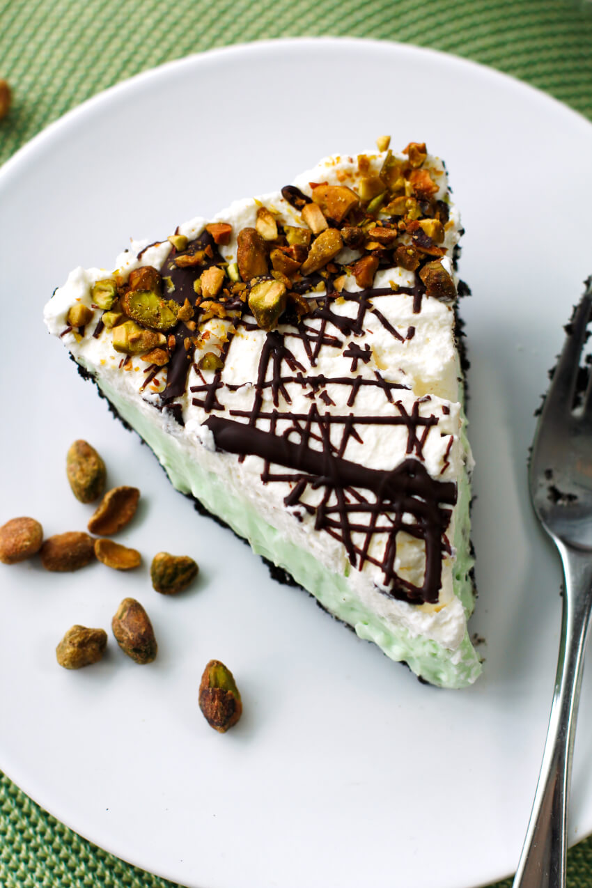 This Pistachio Pudding Pie is a no-bake dessert with an Oreo cookie crust, a creamy pistachio filling, fresh whipped cream, and a pretty chocolate drizzle. It is perfect for parties and picnics!  #nobake #pie #dessert
