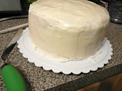 whole cake on a cake platter frosted with white frosting 