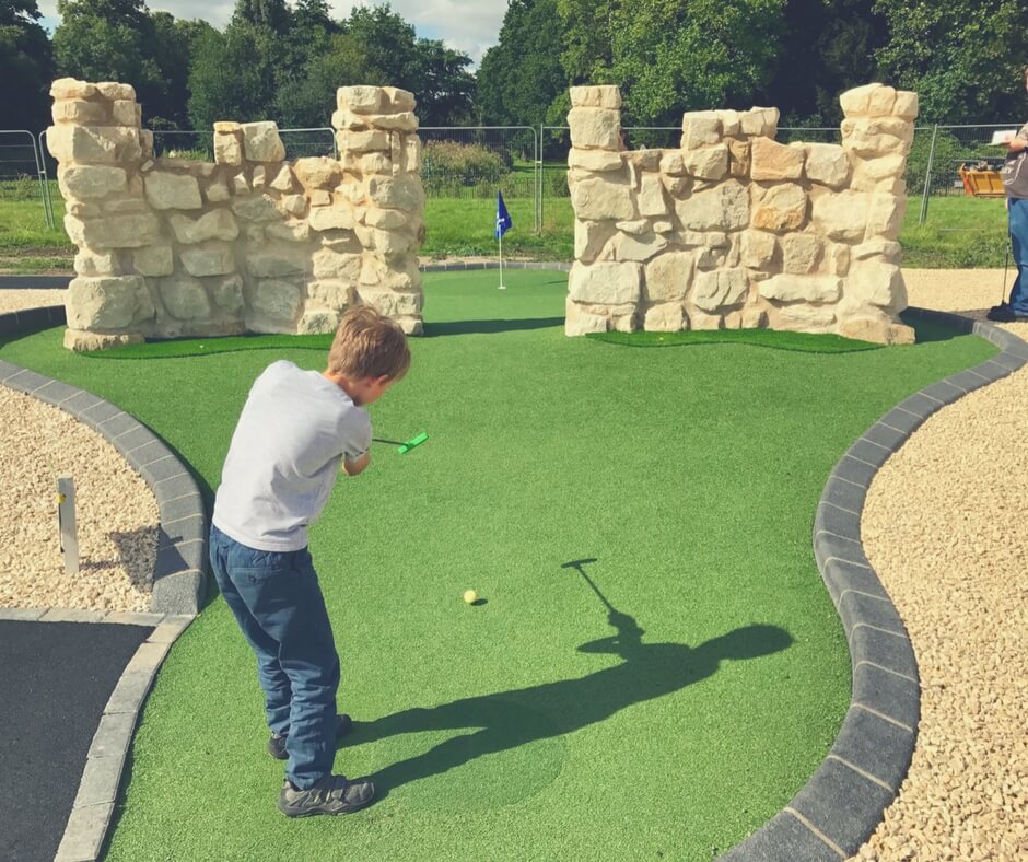 Little boy hits golf ball between two walls
