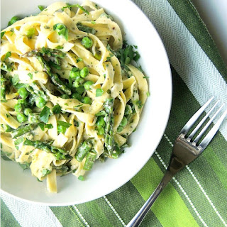 Creamy Pesto Pasta Primavera in a white bowl on a green striped towel with a silver fork