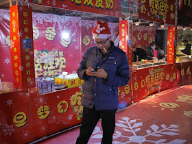man wearing Santa cap smoking and looking at a mobile phone