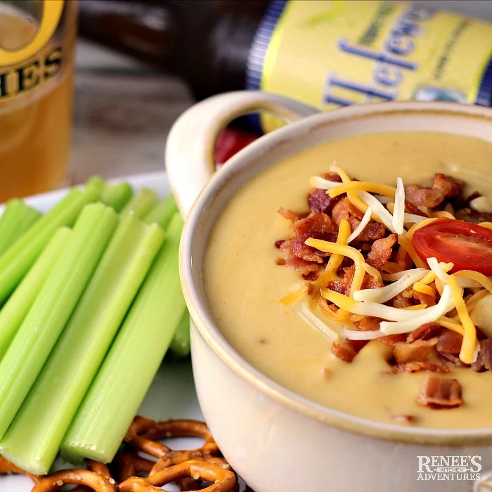 Beer Cheese Dip with Bacon on platter with celery and pretzels, beer in glass and in bottle