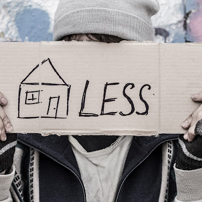 Image of a young person holding a sign that reads homeless