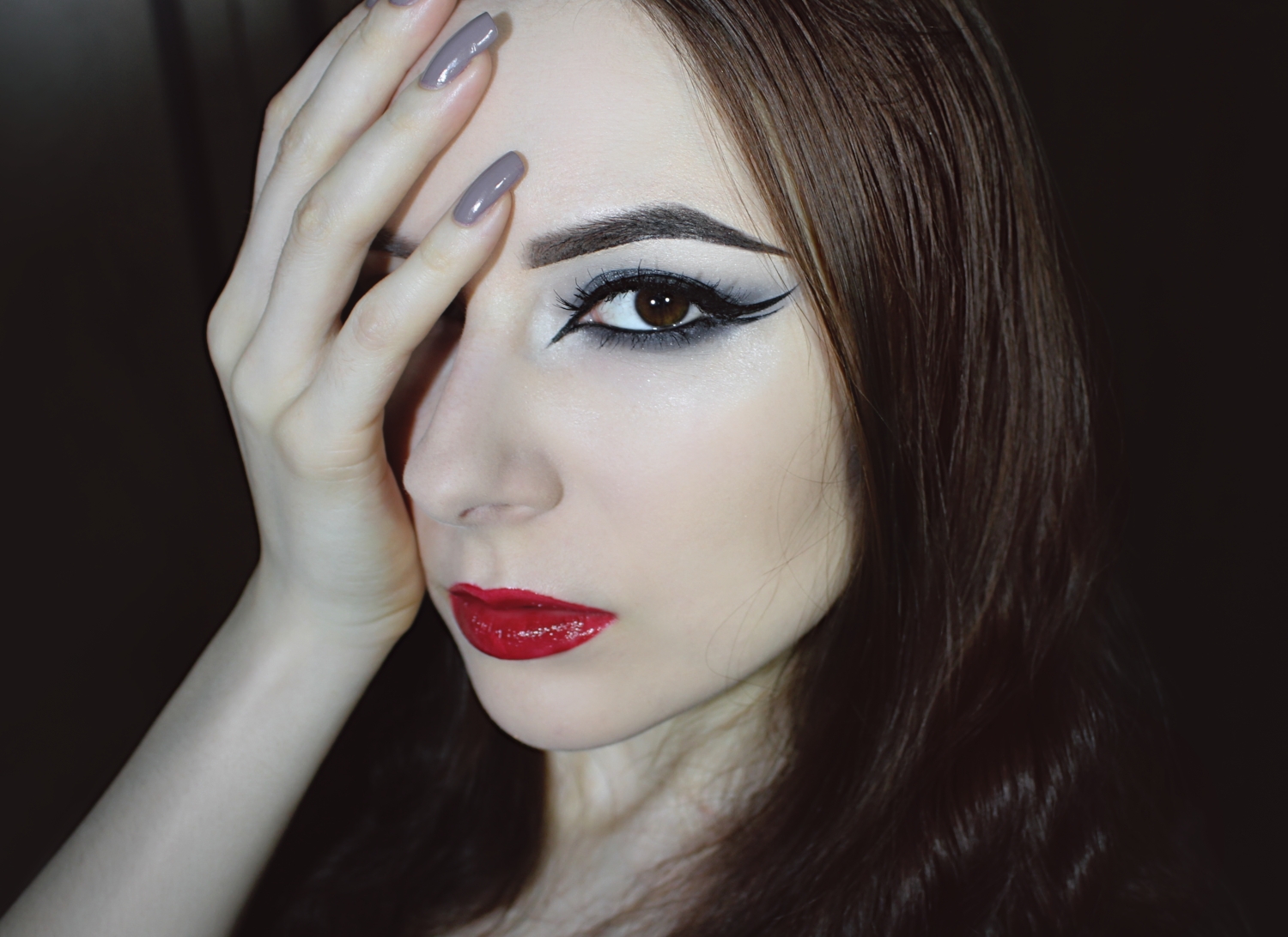 girl with smoky eye makeup, double eyeliner and red glossy lips is showing her makeup