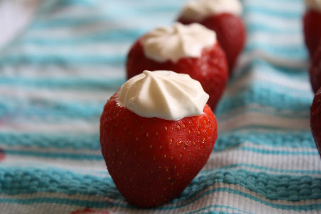 A row of strawberries stuffed with piped fat free cream cheese frosting.