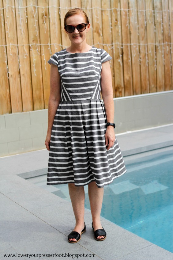 lady modelling a stripe dress in front of a swimming pool
