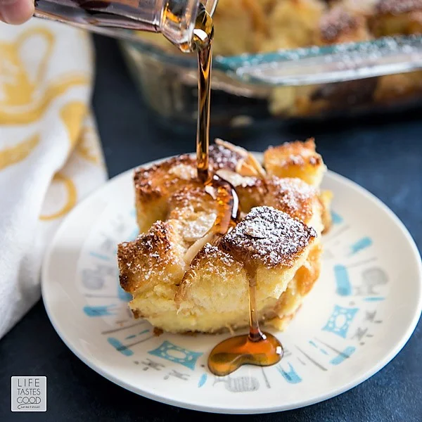 Pouring syrup on Overnight French Toast Casserole on a white plate 