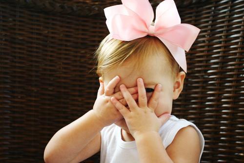 Foto de uma criança tímida, com as mãos na frente do rosto.