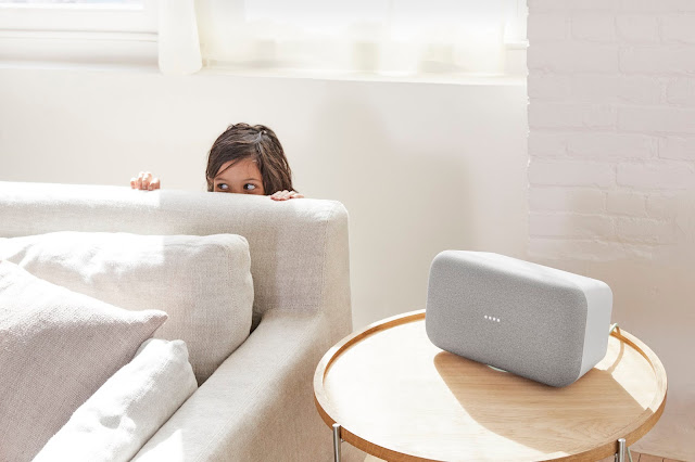 Ein Kind versteckt sich hinter einer Couch, daneben steht ein Google Home Max