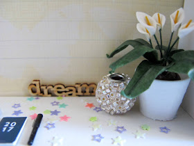 Close up of a one-twelfth scale modern miniature scene of a desk with a 2017 diary and pen, a peace lily and wooden word saying 'dream'.