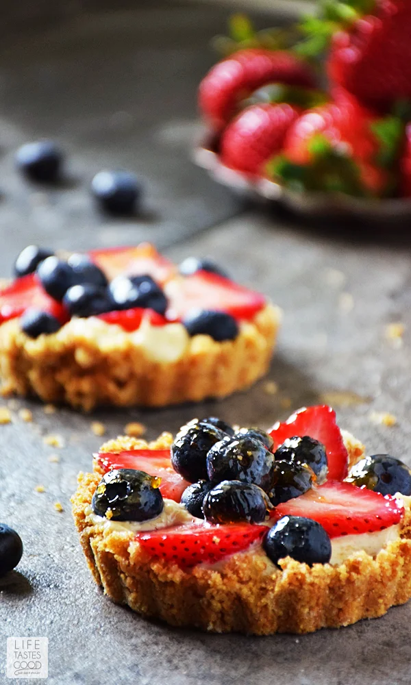 Red, White, and Blue Fruit Tart with a tray of strawberries in the background