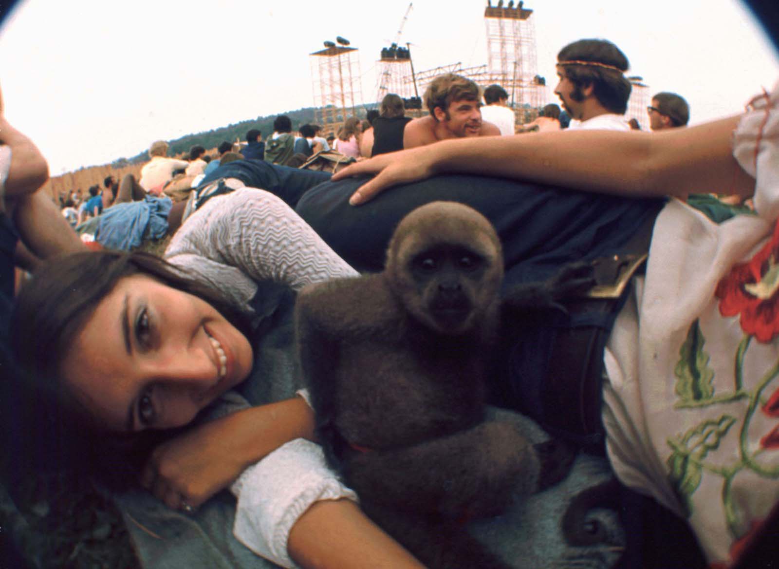 An unidentified woman smiles while her pet monkey sits in the middle of her group.