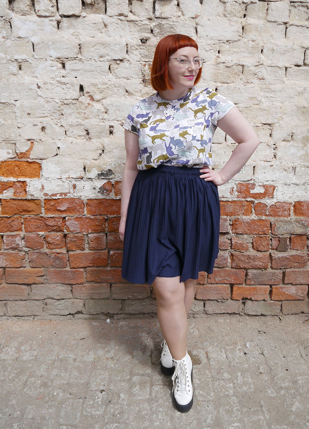 What Helen Wore for Saturday shopping at Tea Green Concept Atelier what Helen wore, red head, See with Iolla, Iolla clear glasses, clear spectacles, Scottish blogger, scottish fashion blogger, Dundee blogger, Dundee event, Dundee, cat lady, crazy cat lady outfit, cat top, H&M outfit, blue skirt, pleated navy skirt, charity shop shoes, white lace up boots, pink blazer, Lucky Dip Club pin, Kate Rowland wooden brooch, Bonnie Bling necklace, Scottish slang necklace, peely wally necklace, Scottish street style, brick wall background, cat print top