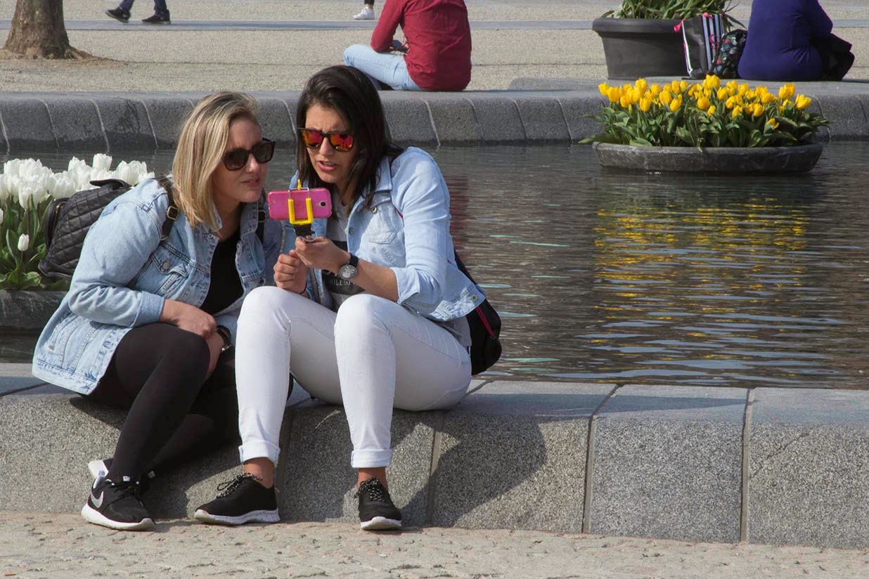 two women with pink cell phone and selfie stick