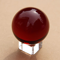 Esfera carmesí en una peana blanca trasparente.