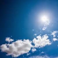 Color photo of blue sky, a few white clouds, and bright sun