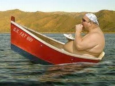 Homem muito gordo comendo enquanto está dentro de um barco minúsculo.