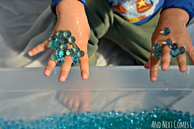 Blue water beads sticking to the top of a child's hands