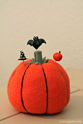 Pumpkin pincushion with handmade Halloween pins.