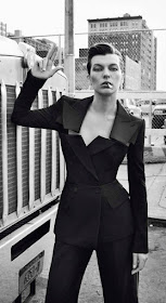 Actress Milla Jovovich smoking, wearing a black pants suit,