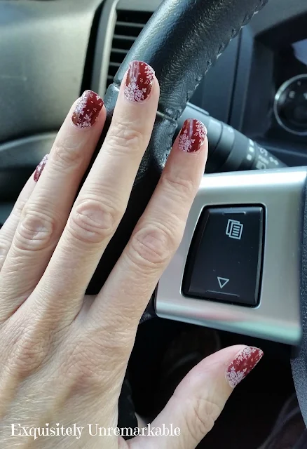 Red FLoral nail wraps on hand on steering wheel