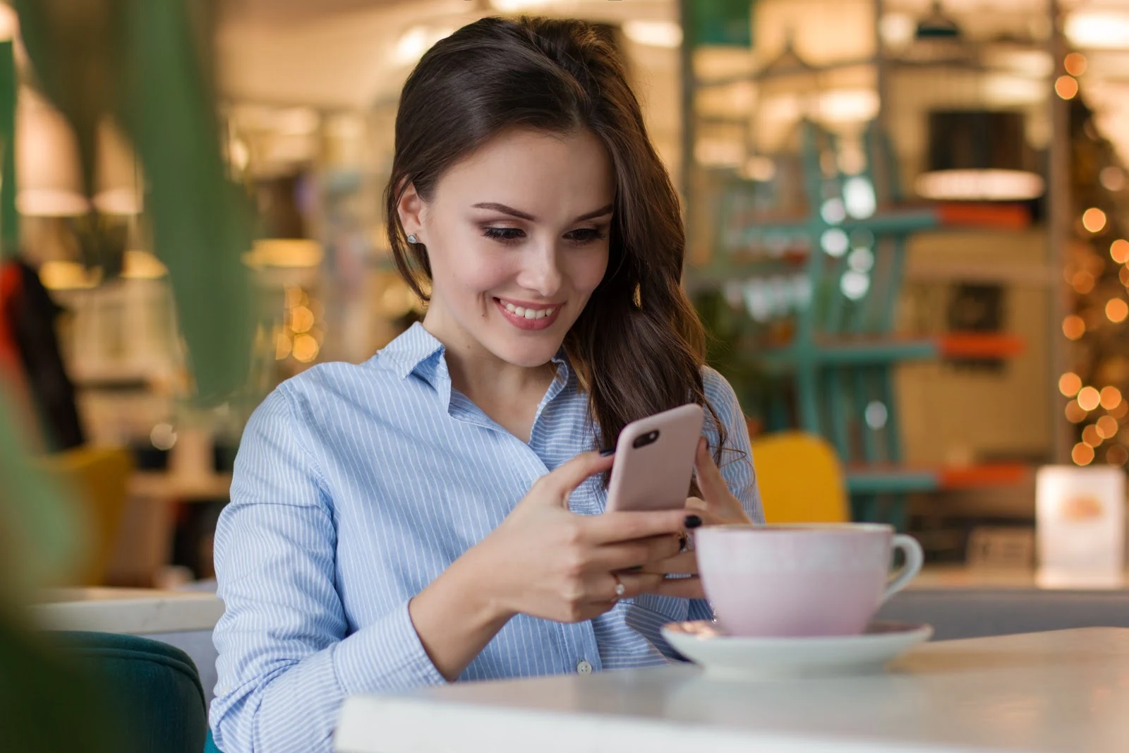 テーブルでスマートフォンを操作する笑顔の女性