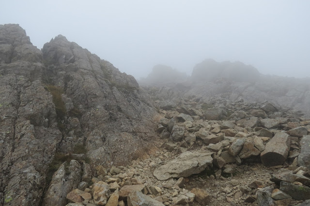 In low cloud, a rocky landscape with no grass or vegetation.