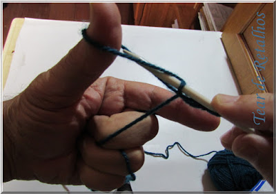 Foto mostrando a agulha retornando ao laço do polegar depois de envolver o laço do indicador na montagem à italiana de pontos do tricô