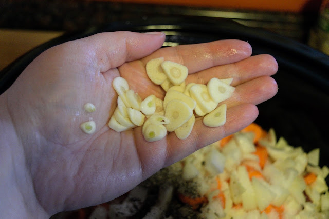 Sliced garlic being added to the crock pot. 