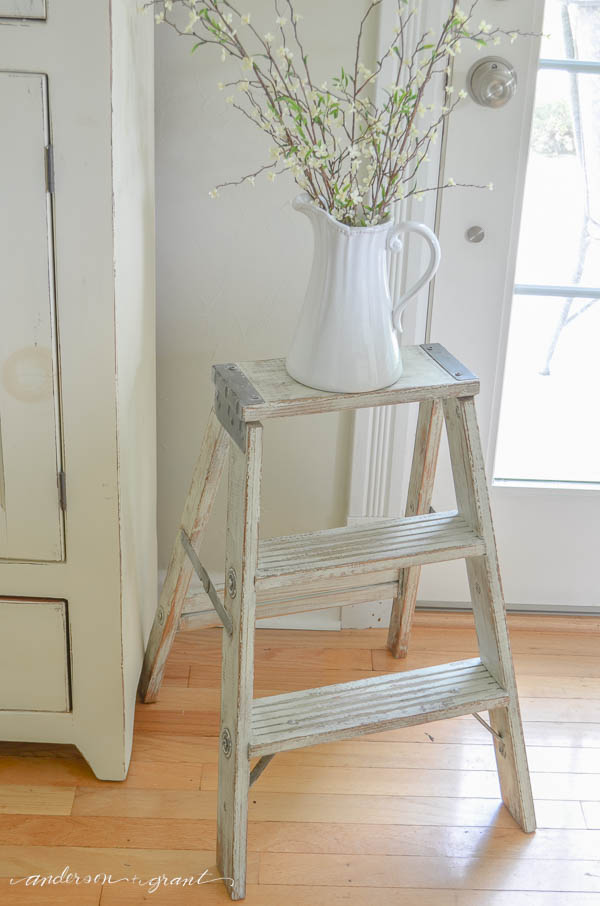 Antique ladder and white pitcher of flowering branches