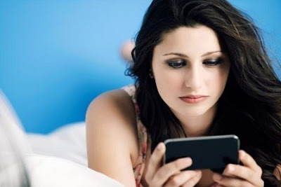 Teenage girl using mobile phone on bed