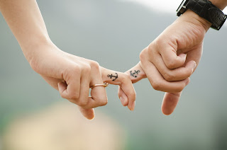 couple with matching anchor tattoo on fingers inter locked 