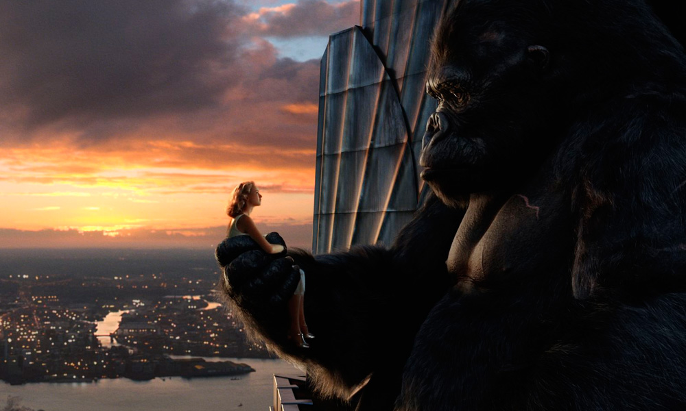Cena do filme King Kong (2005) onde king kong segura uma mulher na mão no topo de um edificio com a cidade ao fundo
