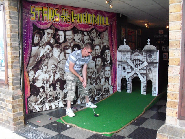 Playing one of the partially outdoors holes at the indoor Crazy Golf course found within the old Windmill Theatre in Great Yarmouth