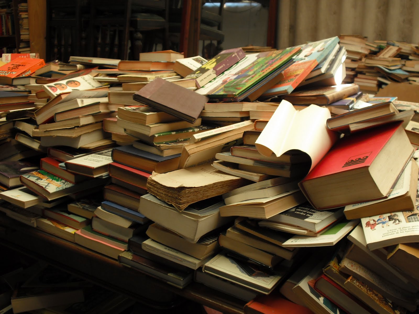 На учительском столе лежала стопка одинаковых учебников. Куча книг. Стопка книг. Стол заваленный книгами. Груда книг.